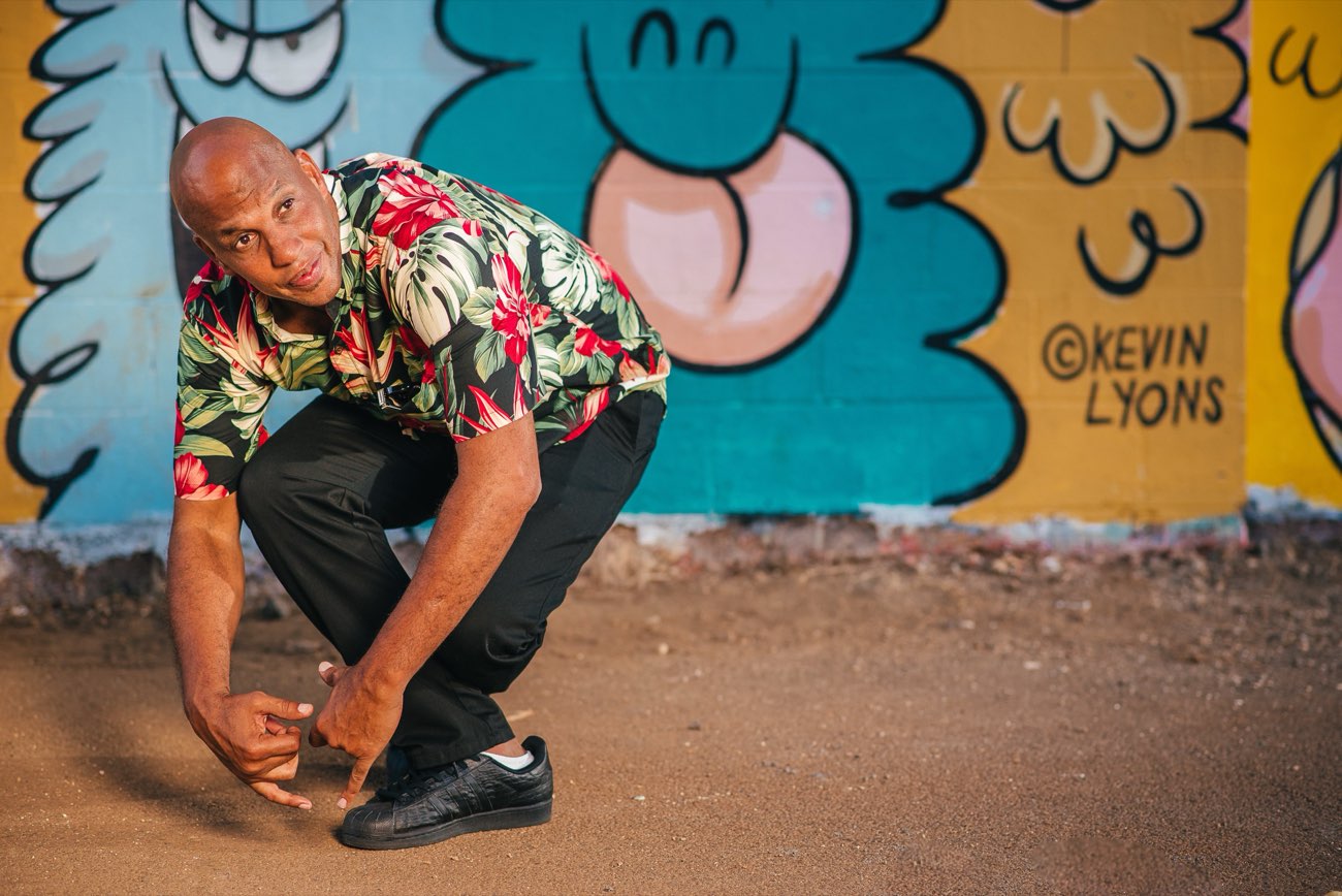 DJ Leanskee portrait in an aloha shirt in front of a street mural
